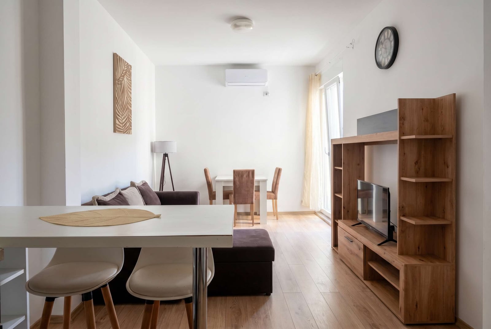Bright living room in an apartment in Budva, Montenegro: modern furniture, dining area, TV stand, and laminate flooring.