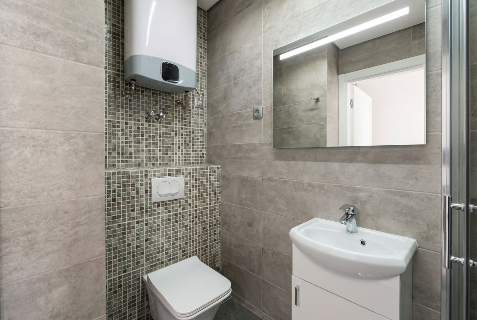 Modernes Badezimmer in einer Wohnung in Bečići, Montenegro: Fliesen, Hänge-WC, Waschbecken und Boiler.