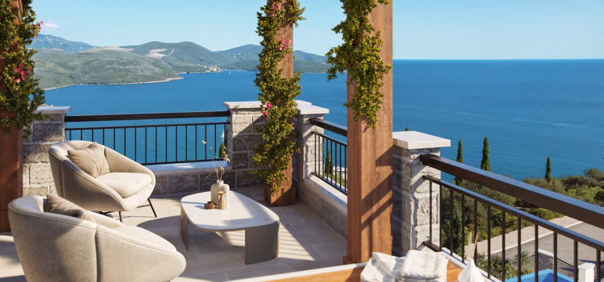 Terrace with soft armchairs and a sea view at the Luštica residential complex, Montenegro: stone finish and floral decor.