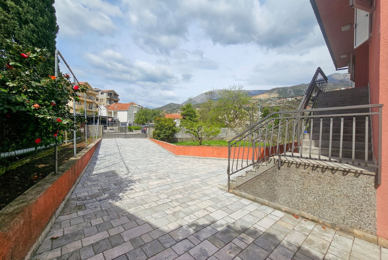 Courtyard of a house in Herceg Novi, Montenegro: paved area, staircase, and mountain view in a private residential area.