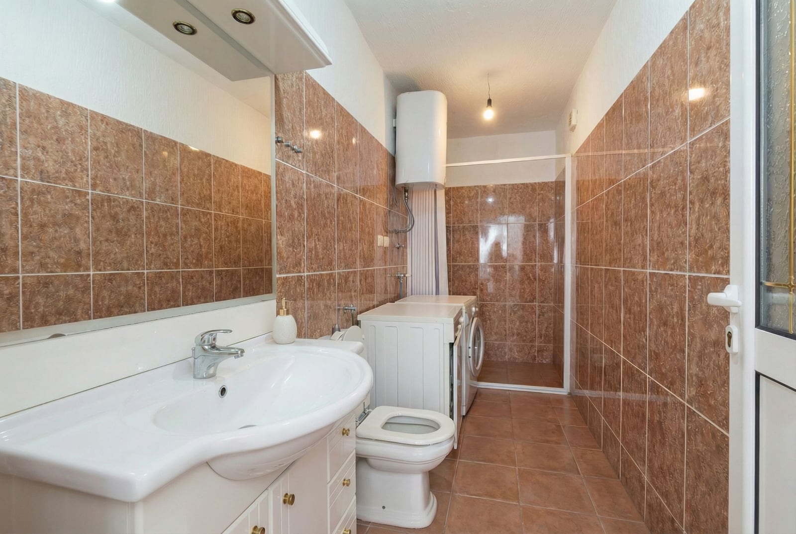 Bathroom with brown tiles, a shower cabin, and a washing machine in a house, Herceg Novi, Montenegro