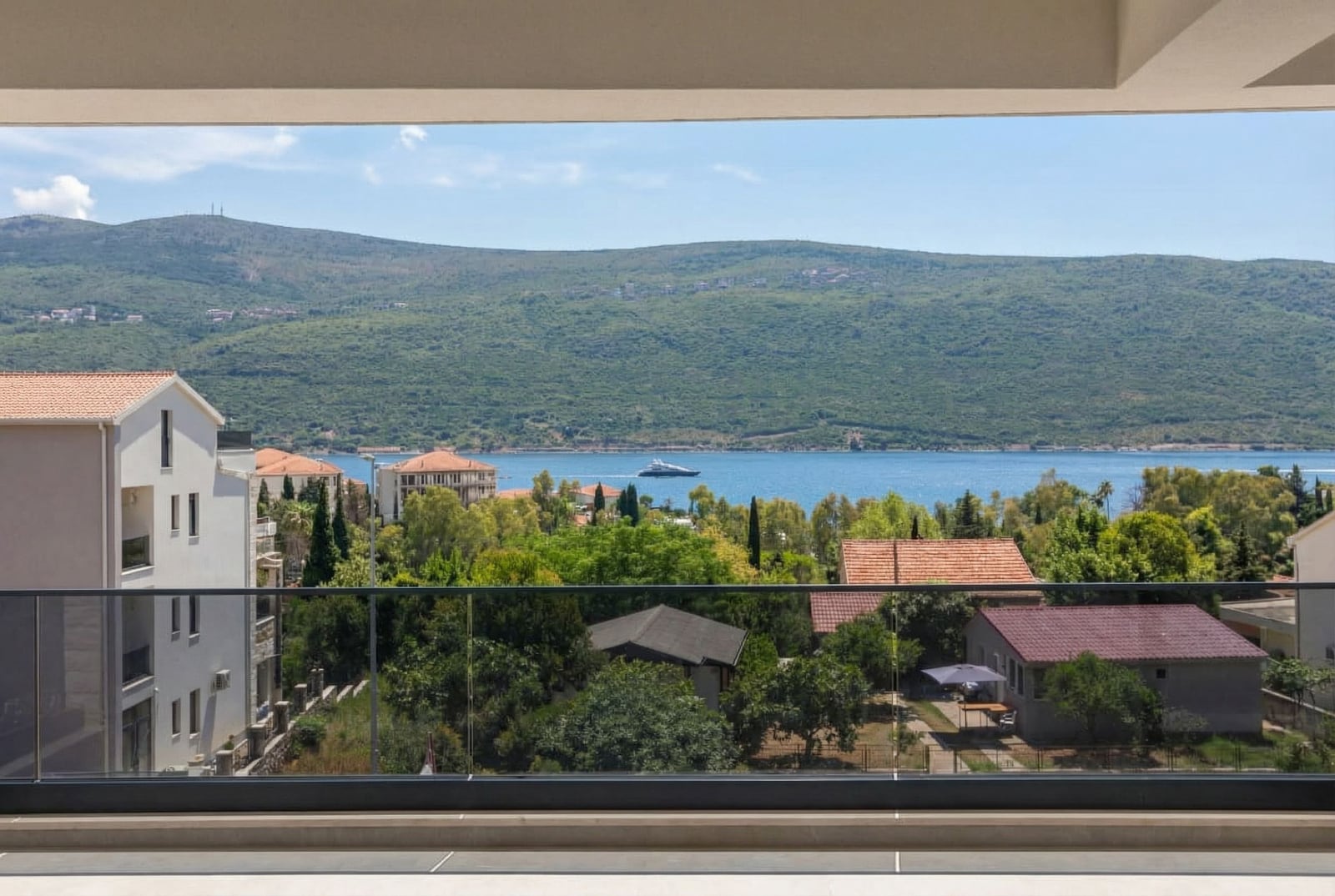 View from the apartment balcony in Kumbor, Montenegro: a panorama of the sea, mountains, and greenery in Herceg Novi.