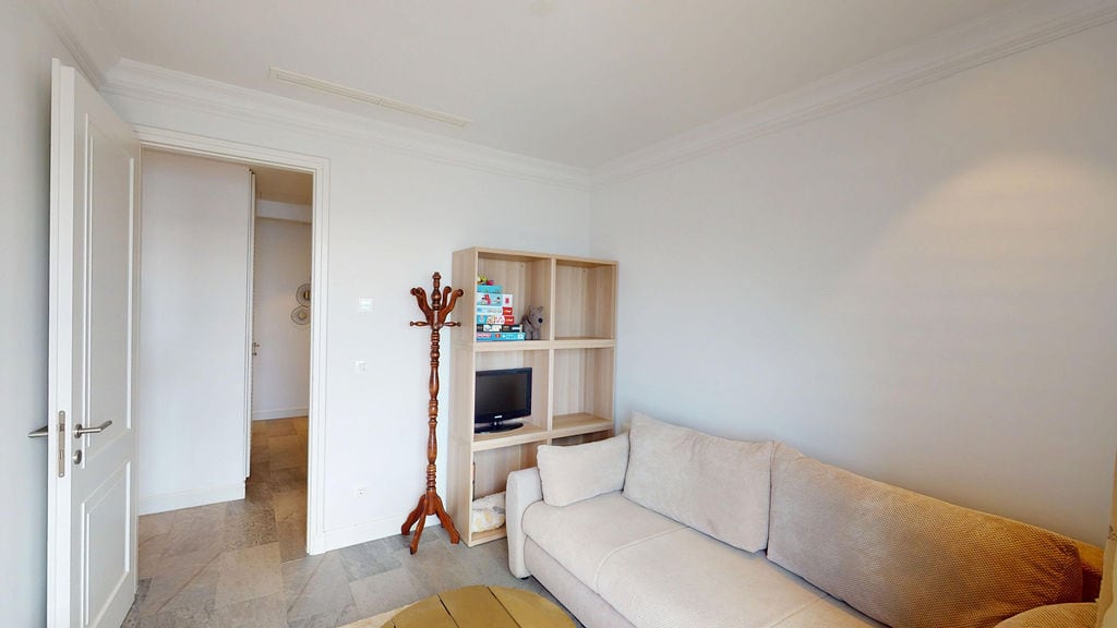 Bright living room with a beige sofa and shelving unit in an apartment at the Luštica residential complex, Montenegro.