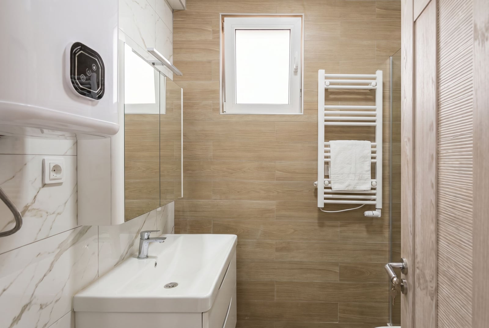 Modern bathroom in an apartment, Herceg Novi, Montenegro: light tiles, sink, mirror, and towel warmer.