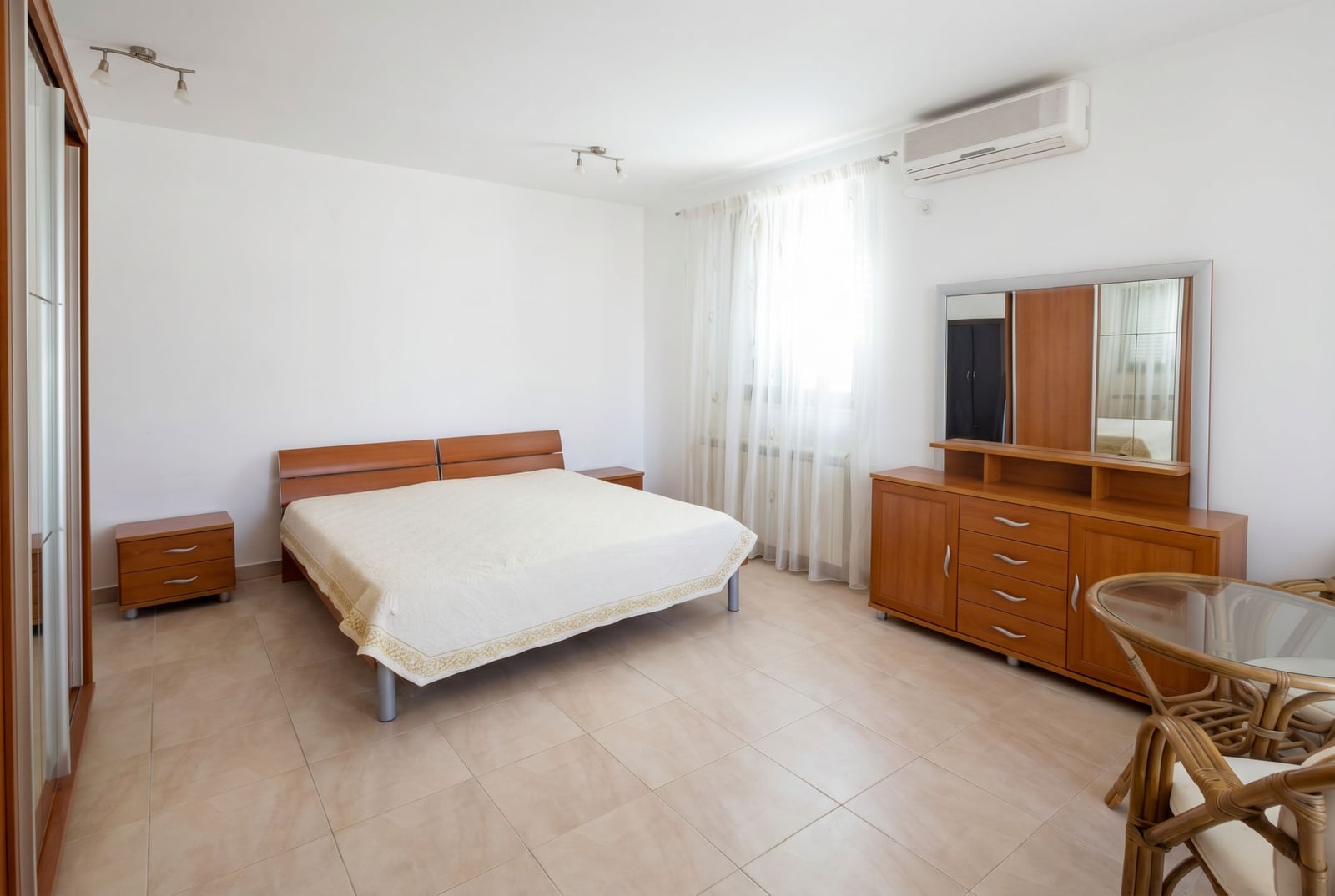 Bright bedroom with a double bed and wooden furniture in a house, Baošići, Montenegro.