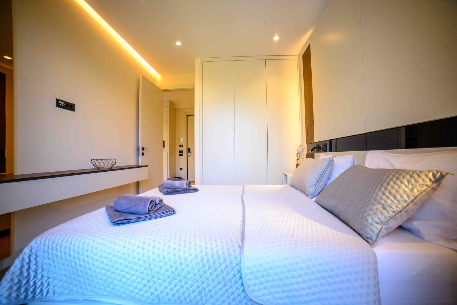 Modern bedroom in an apartment in Bečići, Montenegro: double bed, built-in wardrobe, and hidden lighting.