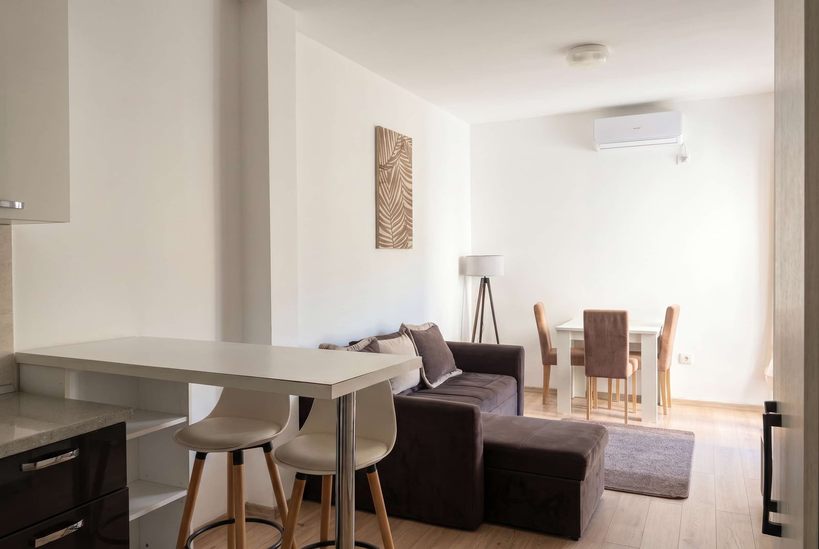 Modern living room with kitchen in an apartment in Budva, Montenegro: sofa, dining area, bar counter, and air conditioner.