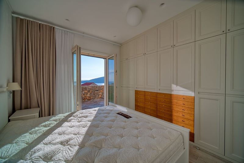 Bedroom in an apartment in Luštica, Montenegro: built-in wardrobe, double bed, and access to a terrace with a sea view.
