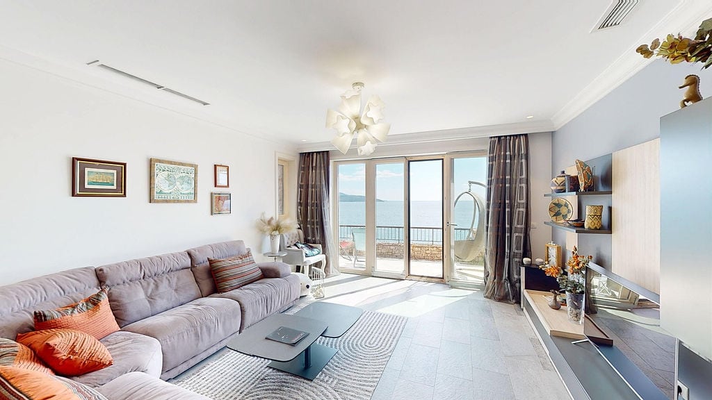 Bright living room with panoramic sea views in an apartment in Luštica, Montenegro: soft sofa, terrace, and stylish decor.