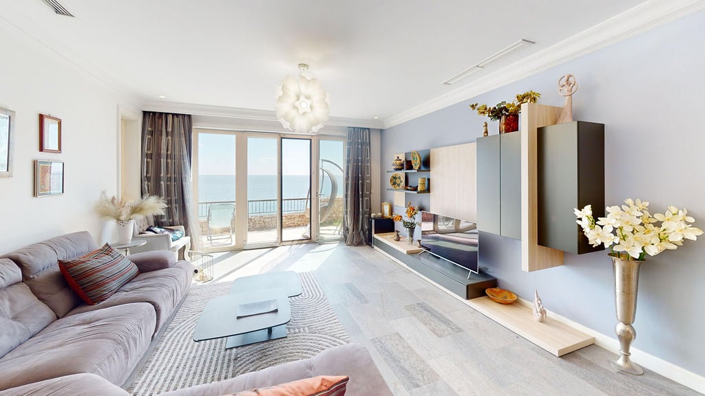 Modern living room with sea view in an apartment, Luštica, Montenegro: soft sofa, TV area, and terrace access.