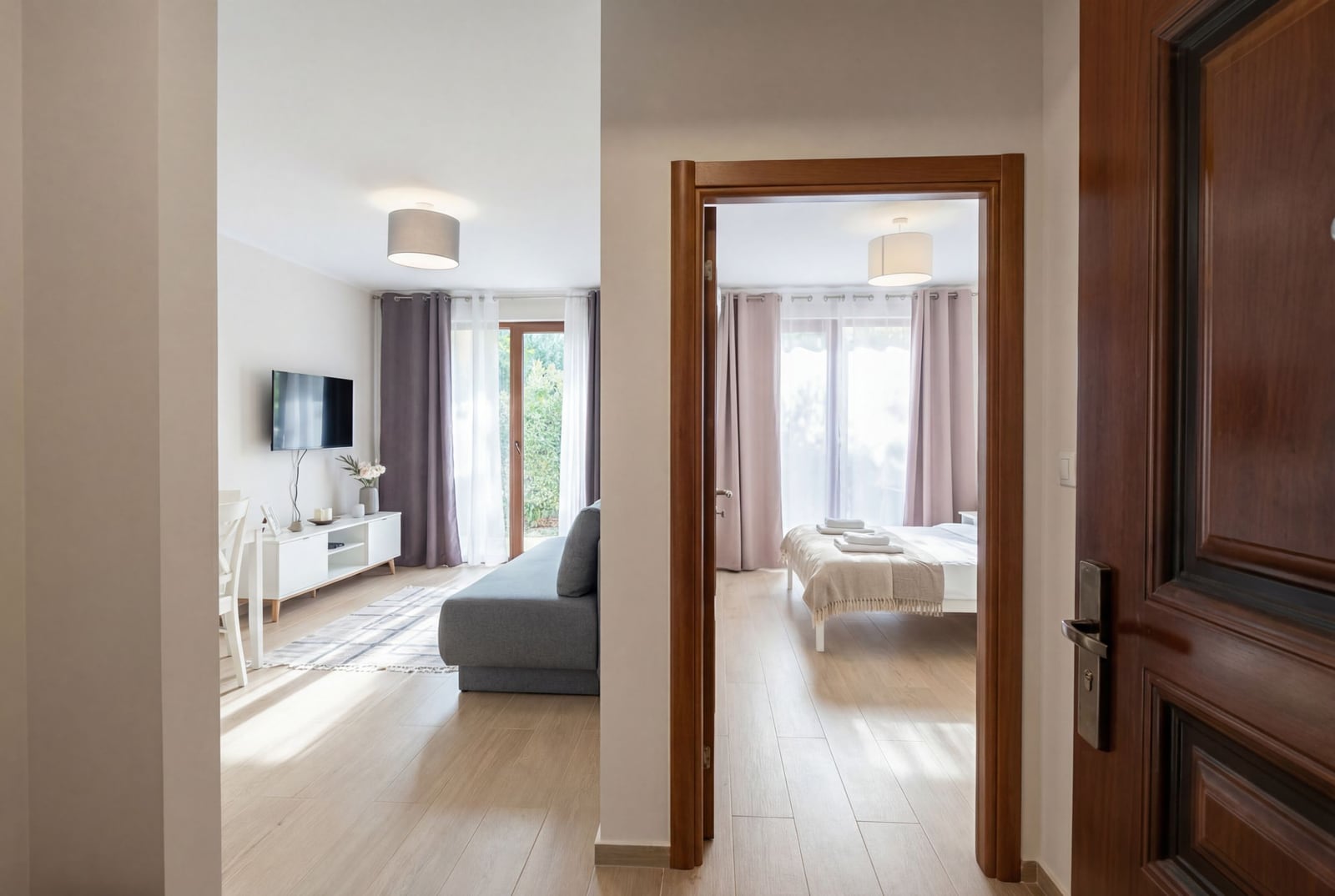 Interior of a modern apartment in Herceg Novi, Montenegro: a bright living room with a sofa and a bedroom with a double bed.