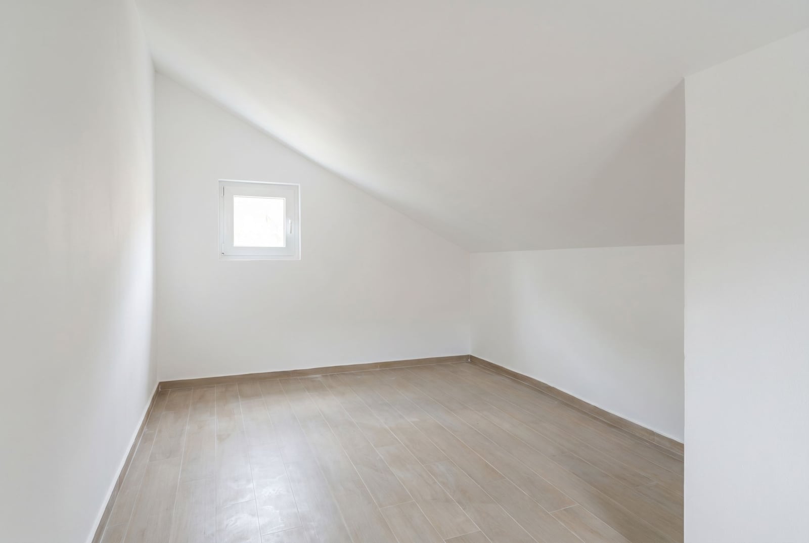 Bright empty attic bedroom with white walls and tiled floor in an apartment, Đenovići, Montenegro.