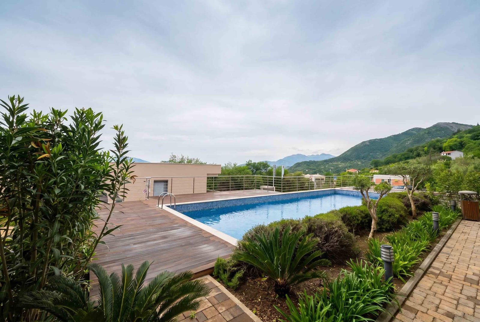 Outdoor pool with wooden terrace and mountain view in a residential complex, Kavač, Montenegro.
