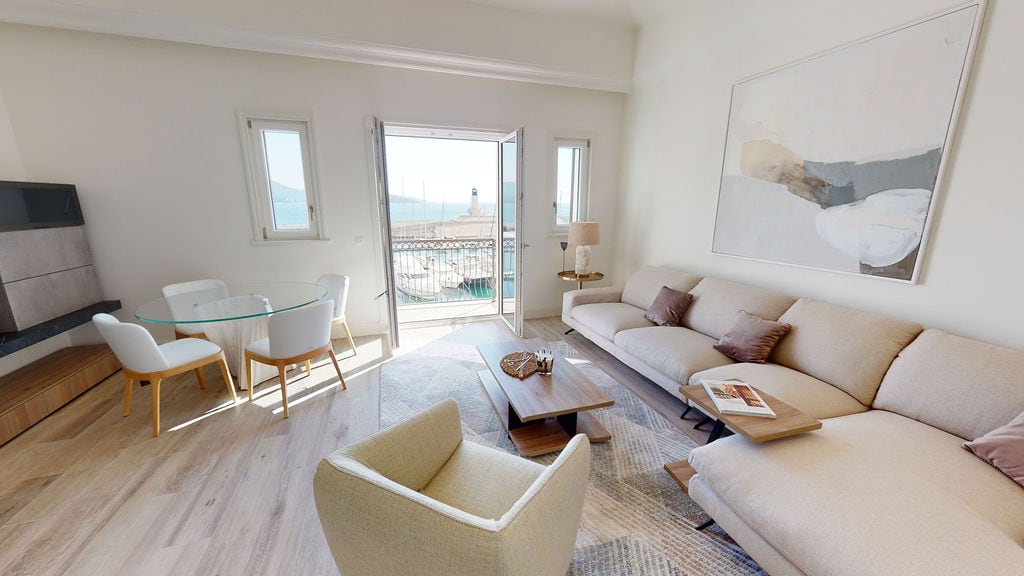 Bright living room in Luštica, Montenegro: modern furniture, dining area, and a view of the yacht marina from the balcony.