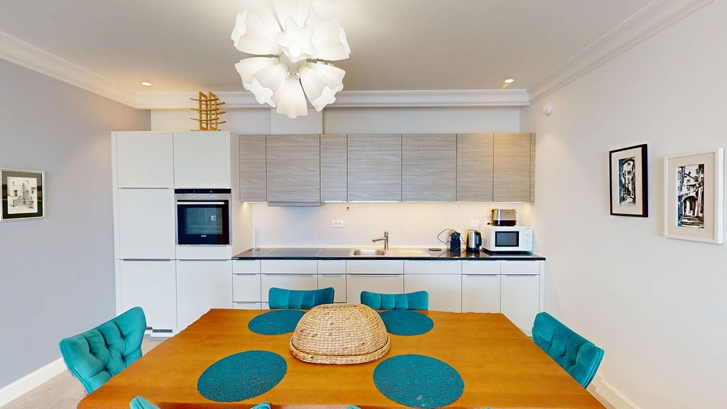 Modern kitchen with dining area in an apartment, Luštica, Montenegro: light-colored kitchen set, wooden table and chairs.