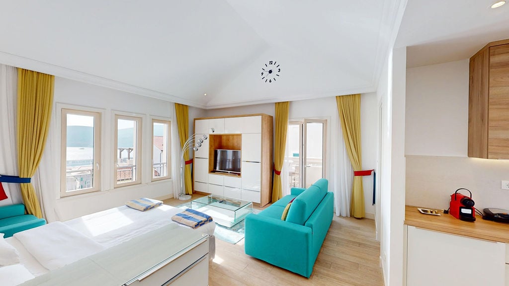 Bright living room in the Krašići apartments, Montenegro: modern furniture, turquoise sofa, and sea view from the windows.