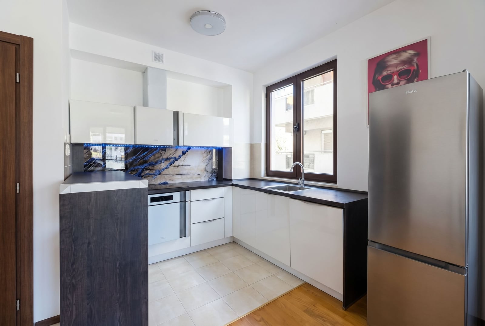 Modern kitchen in an apartment in Budva, Montenegro: white cabinetry, built-in appliances, and a stylish backsplash with lighting.