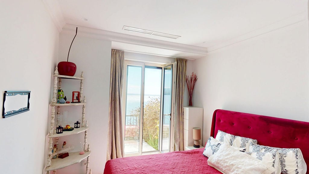 Bedroom with a red bed and sea view in an apartment in Luštica, Montenegro: modern interior with a terrace.