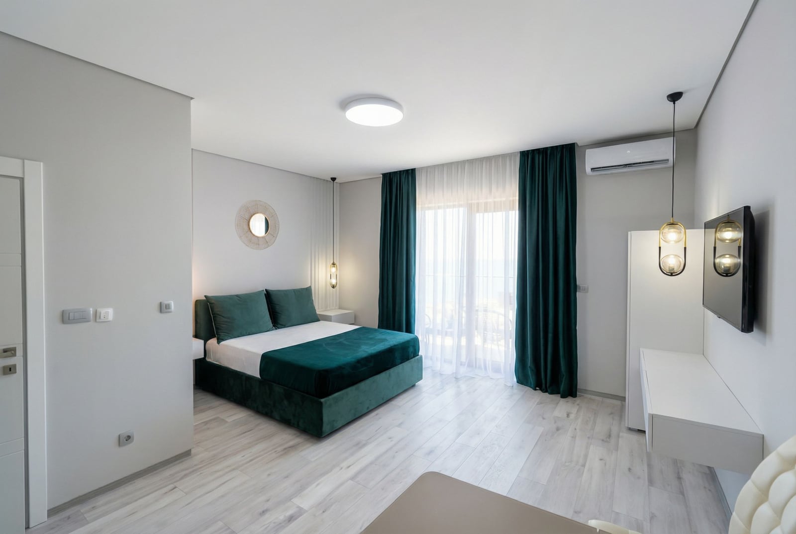 Modernes Schlafzimmer mit smaragdgrünem Bett und Zugang zum Balkon in einer Wohnung in Bečići, Montenegro.