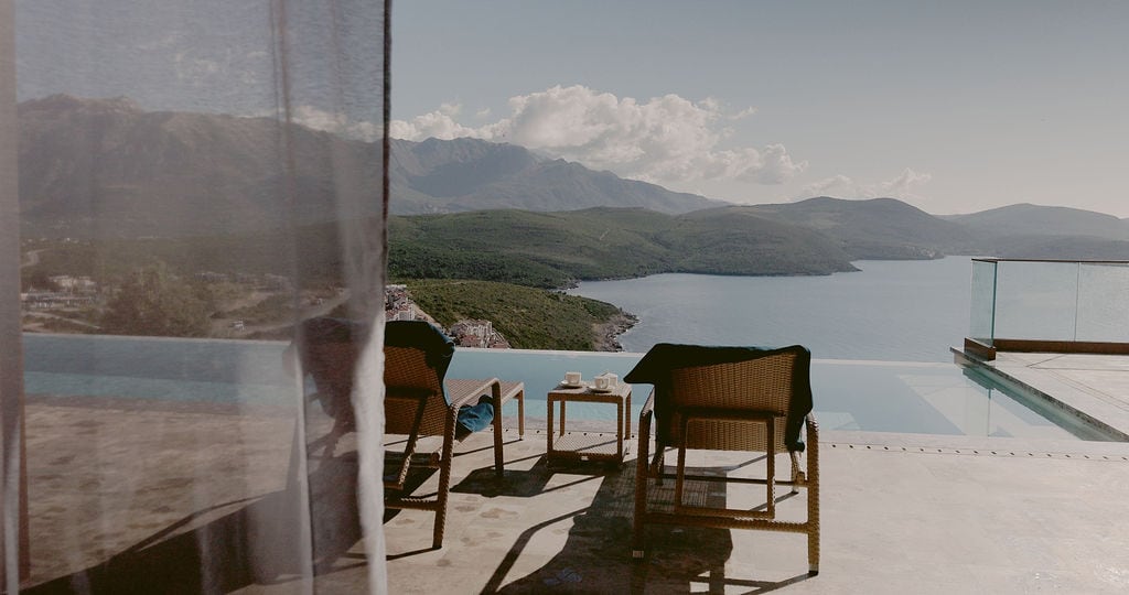 Townhouse terrace in Luštica, Montenegro: infinity pool, woven sun loungers, and panoramic views of the sea and mountains.