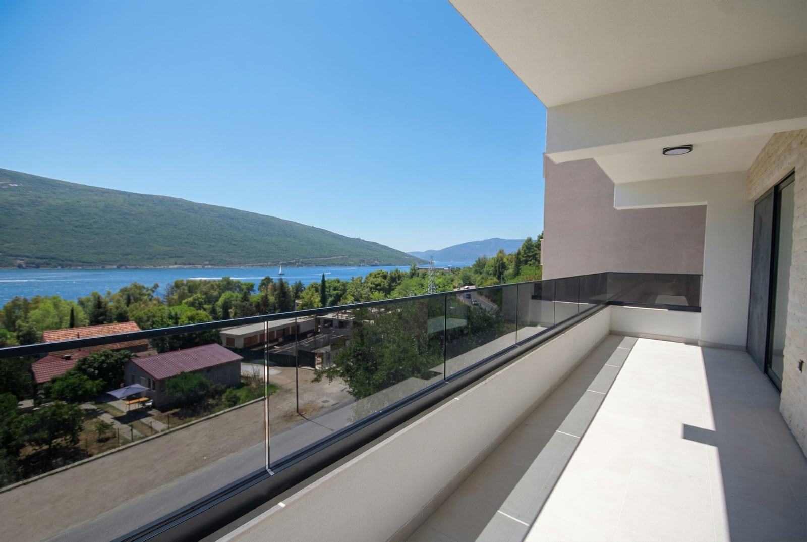Spacious balcony with panoramic views of the sea and mountains in an apartment, Kumbor, Montenegro, modern finishes and railing.