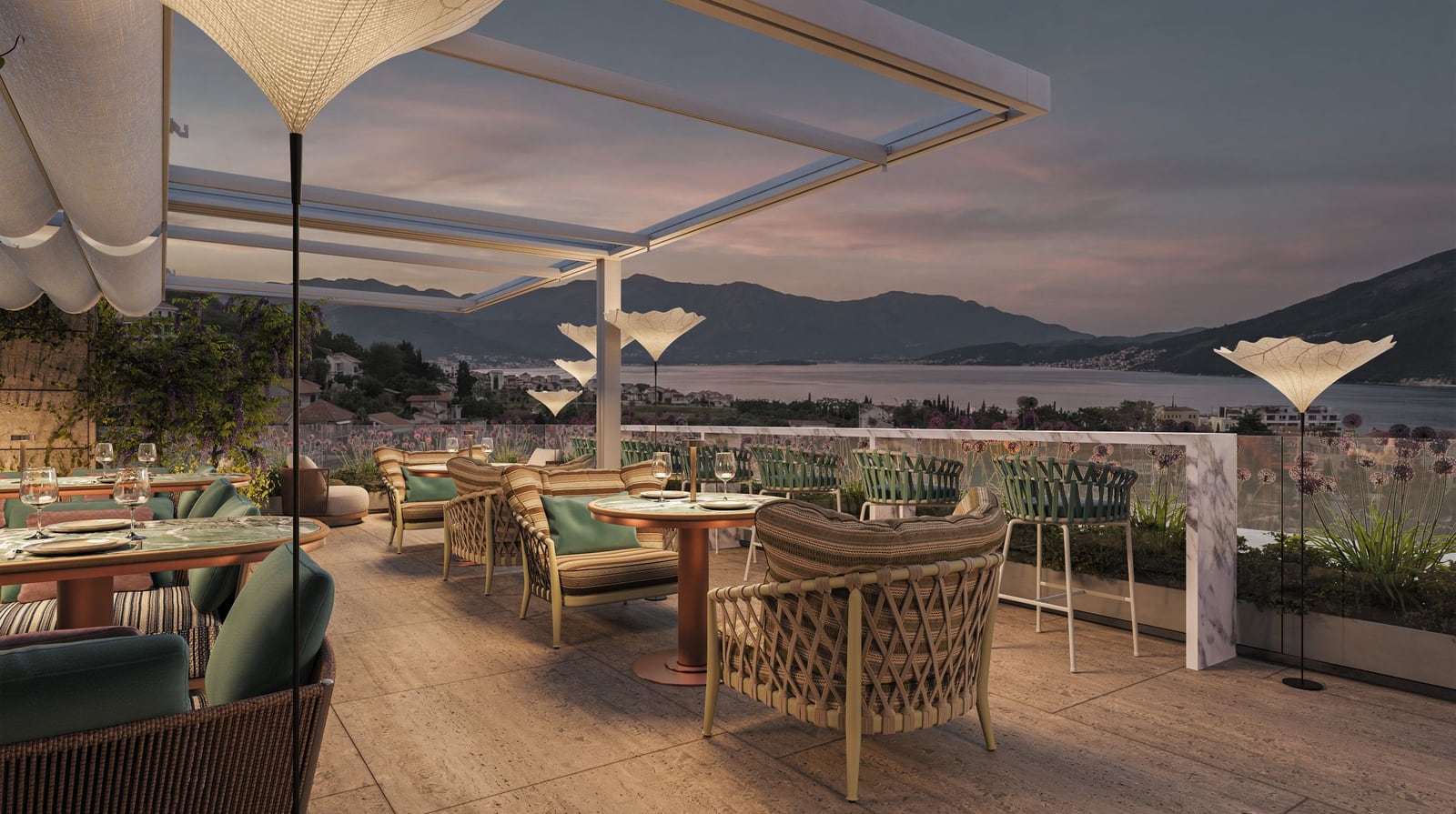 Restaurant terrace in the Kumbor residential complex, Herceg Novi, Montenegro: wicker furniture, panoramic view of the sea and mountains at sunset.