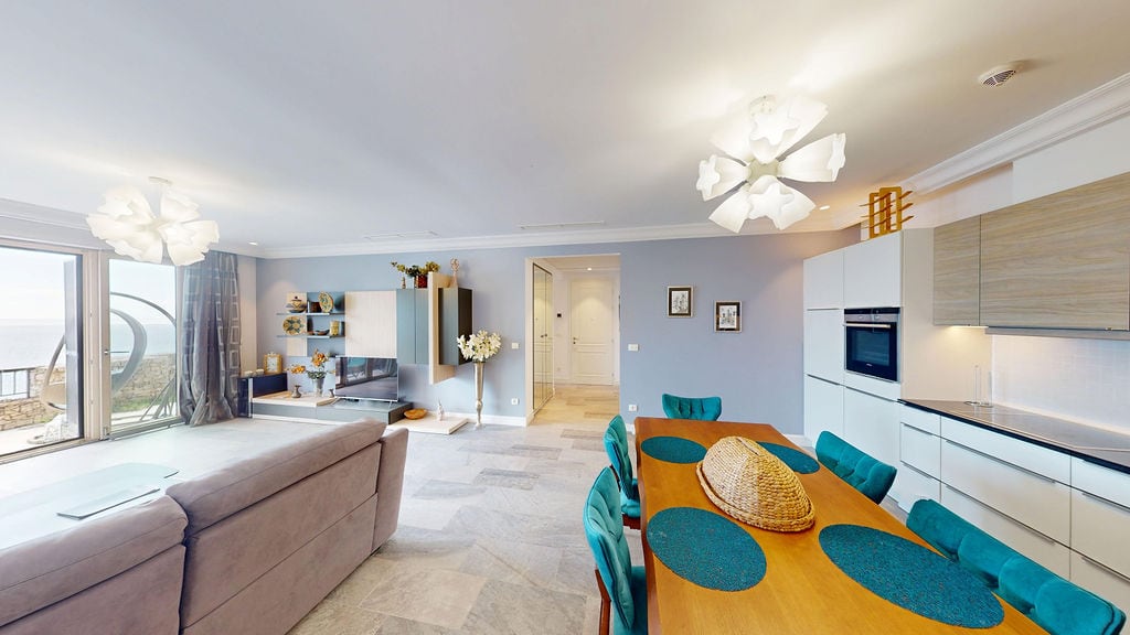 Modern living room with kitchen in an apartment, Luštica, Montenegro: dining area, upholstered furniture, and sea view.