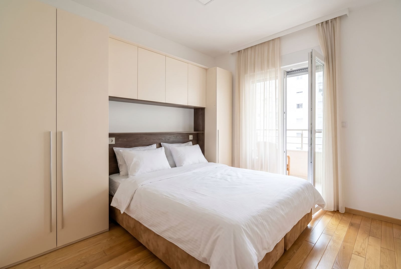 Bright bedroom with a double bed and built-in wardrobe in an apartment in Budva, Montenegro, with access to the balcony.