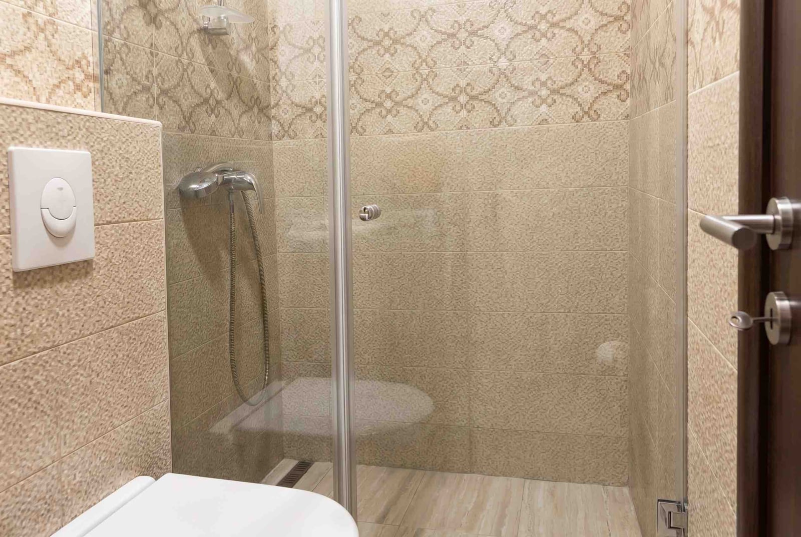 Modern bathroom in an apartment, Budva, Montenegro: shower cabin with a glass partition and beige tiles.