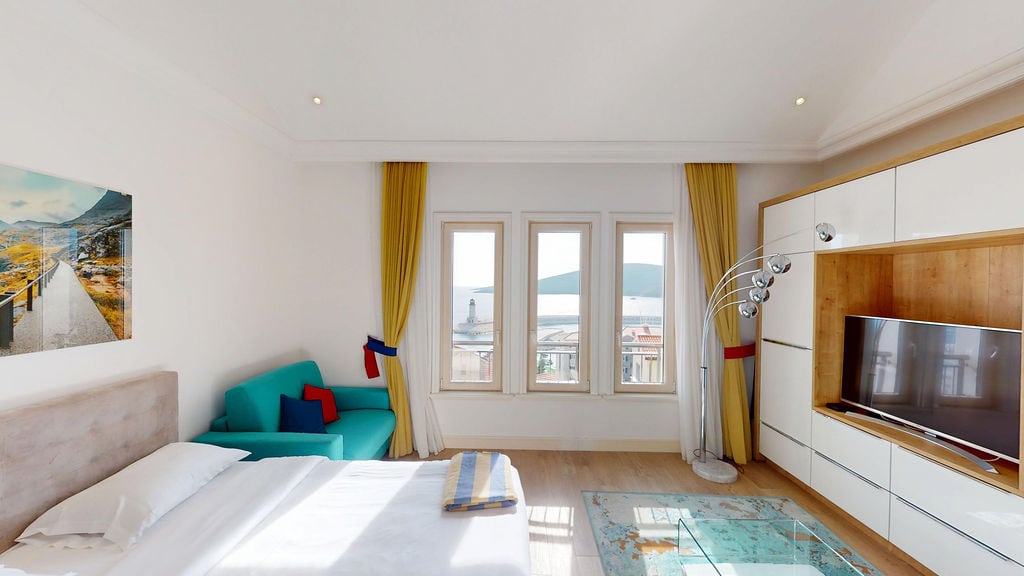 Bedroom in an apartment in Krašići, Montenegro: sea view, modern furniture, bright sofa, and TV area with panoramic windows.
