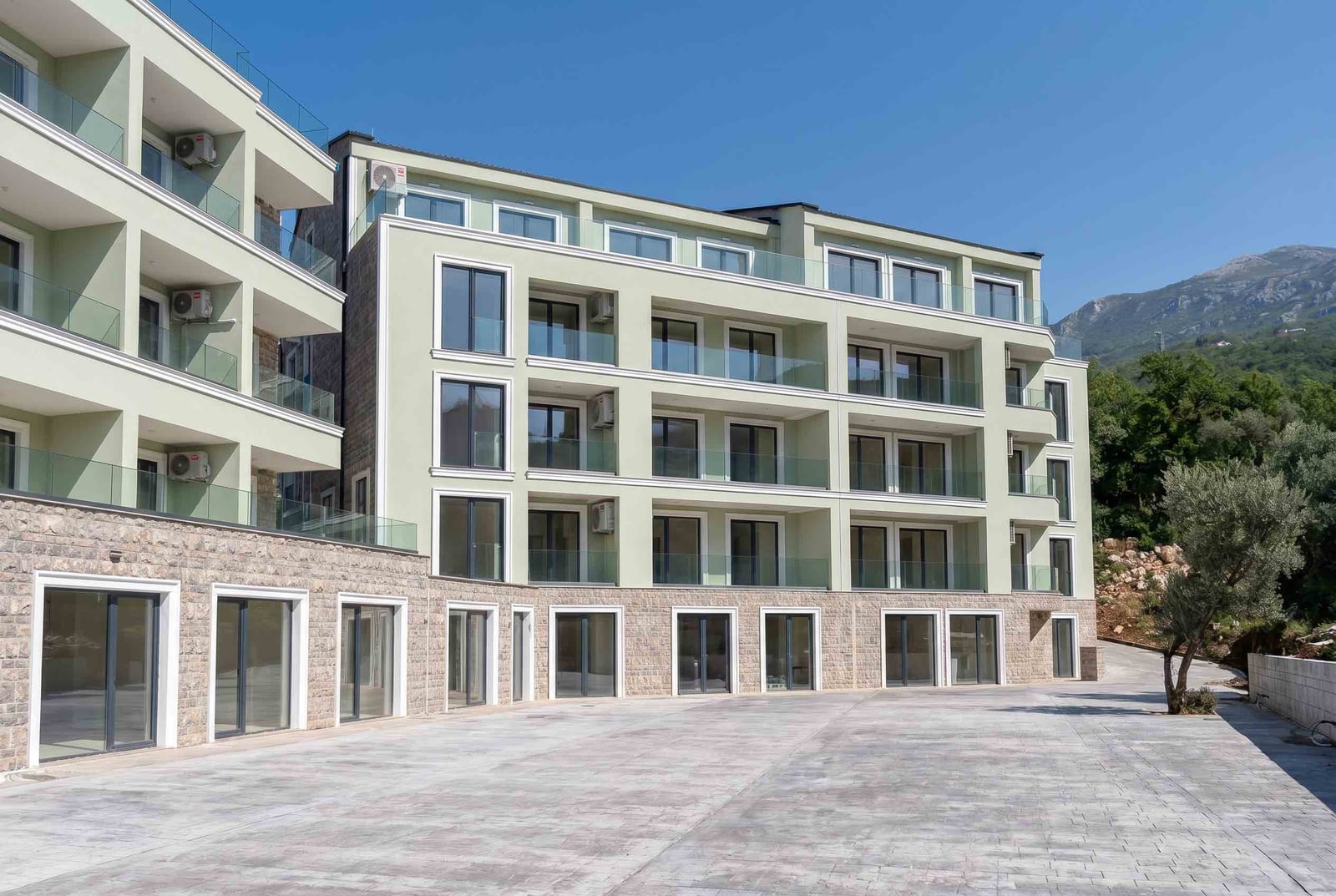 Modern residential complex with terraces in Pržno, Montenegro: building facade with panoramic windows and stone cladding.