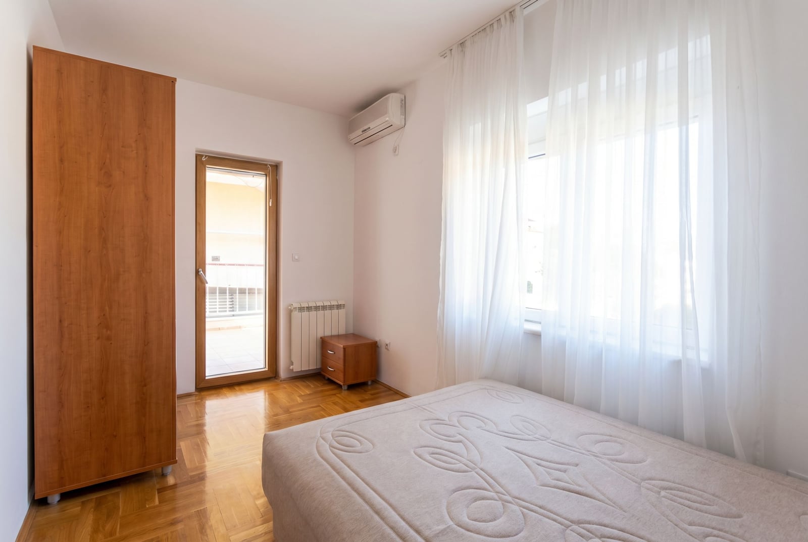 Bright bedroom with a double bed, wardrobe, and access to the balcony in a house, Baošići, Montenegro.