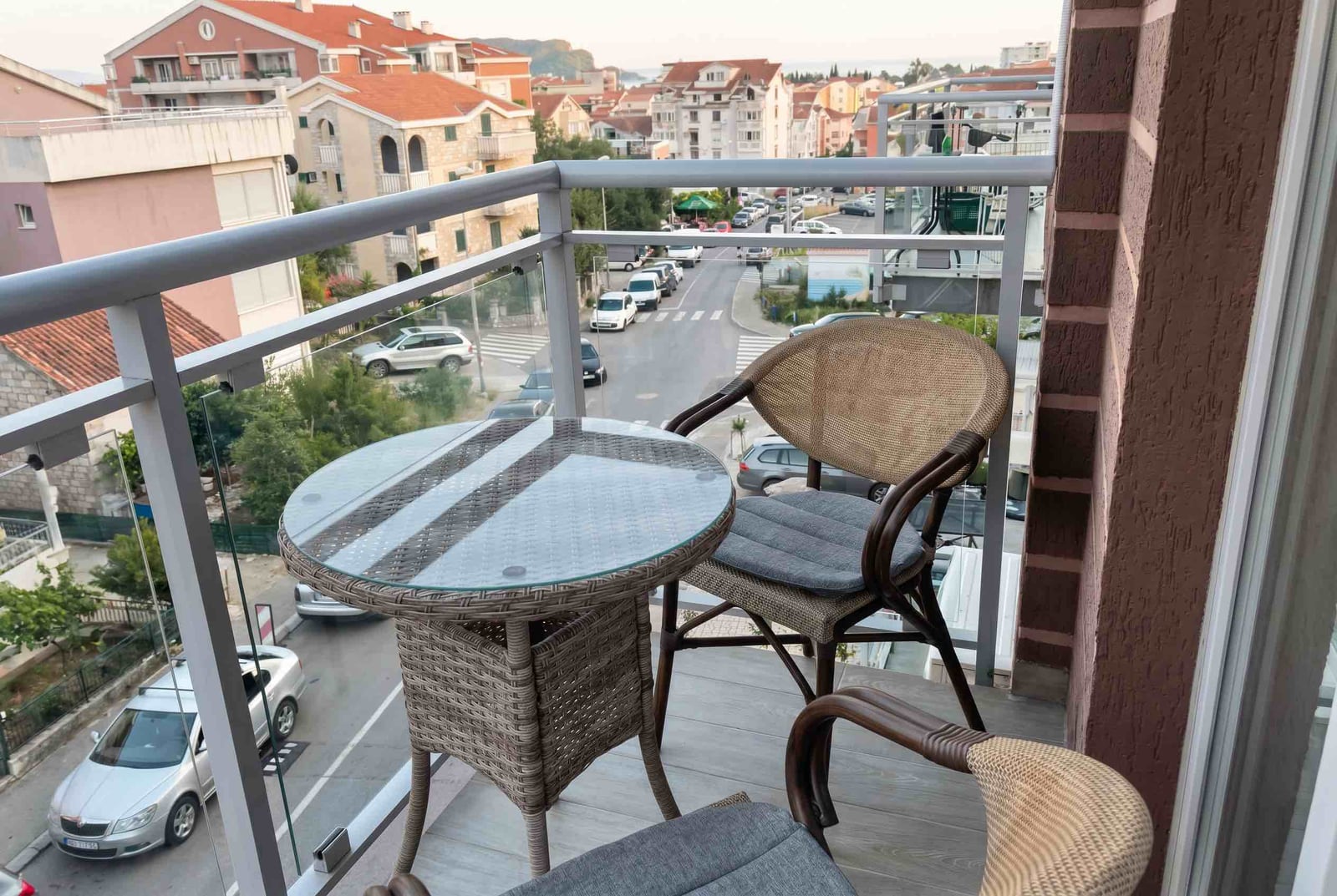 Balcony with wicker furniture and city view in an apartment in Budva, Montenegro. Cozy outdoor lounge area.